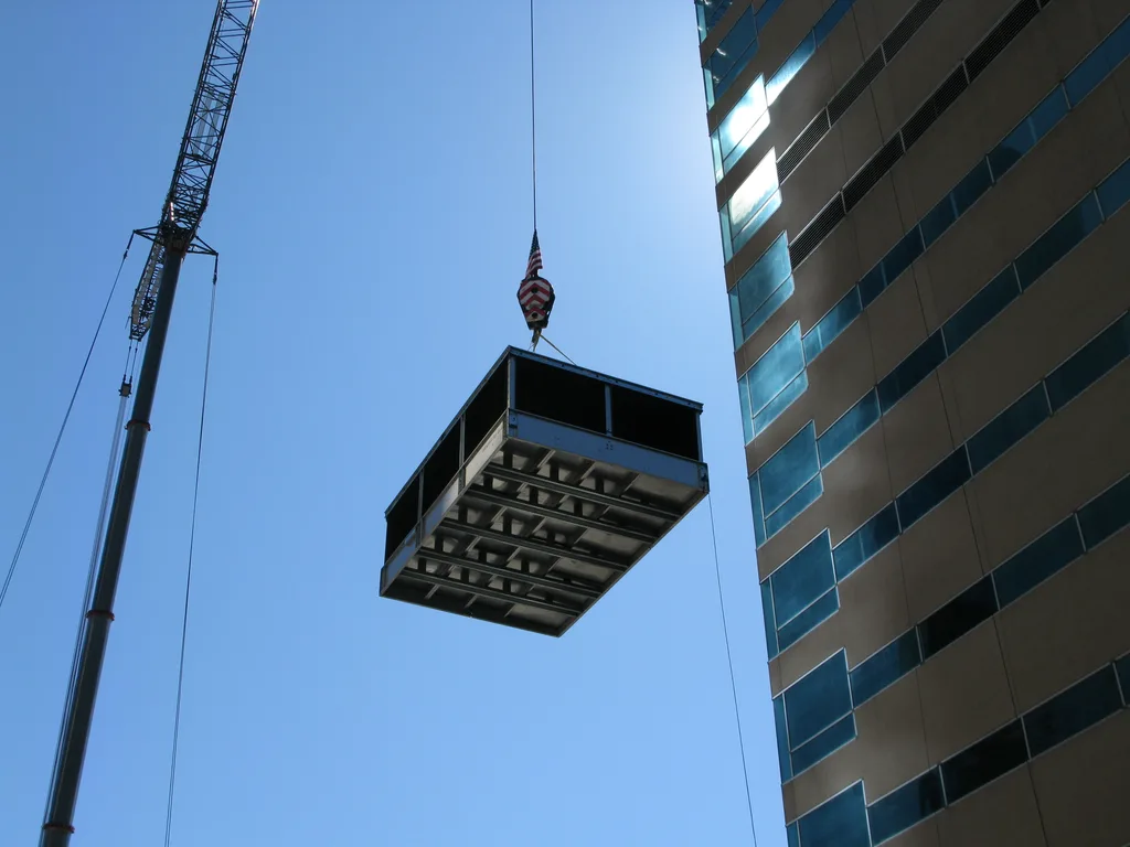 An HVAC unit being raised by a crane to be installed in an office high-rise
