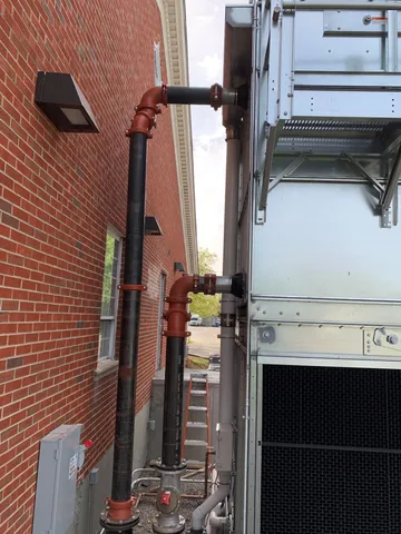 Behind a cooling tower pipes connect to the building